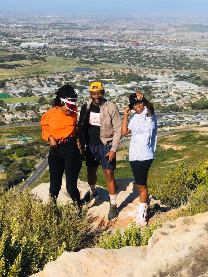 Three friends at a mountain summit over Cape Town